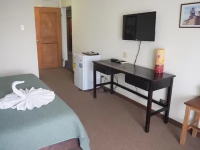 a room with a desk with a television and a bed at Nuevo Maragato Hotel & Hostel in San José