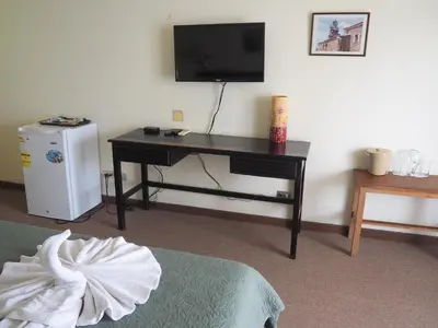 a room with a desk with a television and a refrigerator at Nuevo Maragato Hotel & Hostel in San José