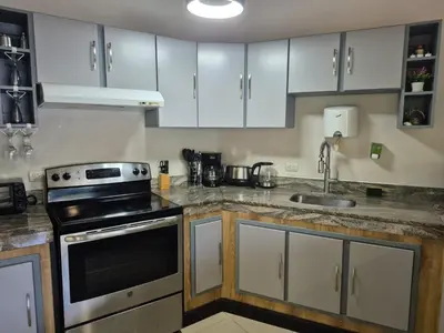 a kitchen with white cabinets and a stove and a sink at MonteMar Beach Condo At Playa hermosa in Sardinal