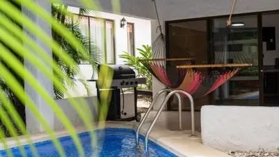 a swimming pool with two chairs and a grill at MonteMar Beach Condo At Playa hermosa in Sardinal