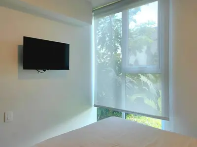 a bedroom with a flat screen tv and a window at 804 SECRT Sabana Hermoso Apartamento con Aire Acondicionado in San José