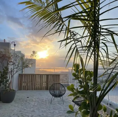 a patio with a chair and a sunset in the background at 804 SECRT Sabana Hermoso Apartamento con Aire Acondicionado in San José