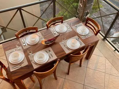 a wooden table with plates and glasses on a balcony at Rooftop balcony oceanfront PH condo with King beds in Jacó