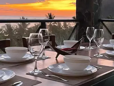 a table with plates and wine glasses on a table with a view at Rooftop balcony oceanfront PH condo with King beds in Jacó