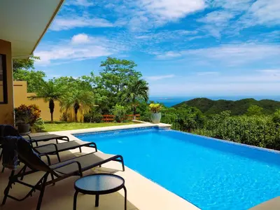 a swimming pool with chairs next to a house at Casa Sol Azul - remarkable, ocean view 4 BR House in Potrero in Potrero