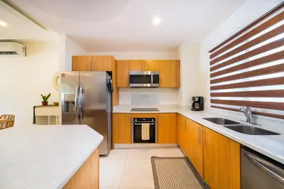a kitchen with wooden cabinets and a stainless steel refrigerator at Condo Casa Blanca 6 - modern 2BR,2BA near to Beach & Town in Potrero
