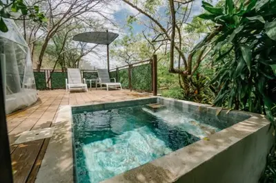 a swimming pool with two chairs and a table at Glamping Tortuga Verde in Ocotal