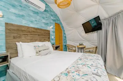 a bedroom with a large bed and a tv at Glamping Tortuga Verde in Ocotal