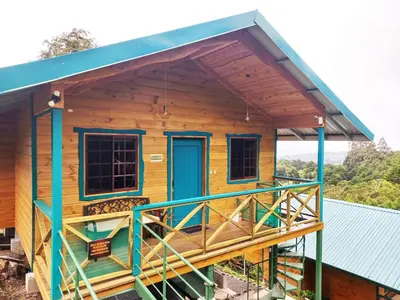 a wooden house with a blue door and a balcony at Cabañas Emerald Forest in Concepción
