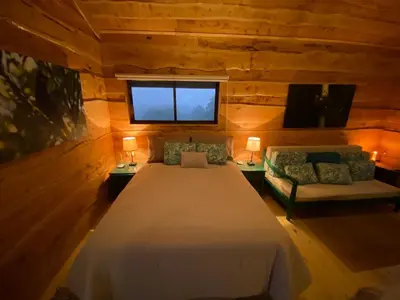 a bedroom with a bed and a couch and a window at Cabañas Emerald Forest in Concepción