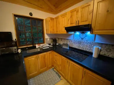 a kitchen with wooden cabinets and a black counter top at Cabañas Emerald Forest in Concepción