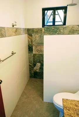 a bathroom with a toilet and a window at VILLA SIMONE ARENAL French Ecolodge in Tilarán