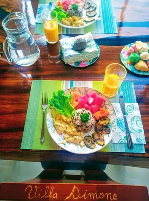 a table with two plates of food and two glasses of orange juice at VILLA SIMONE ARENAL French Ecolodge in Tilarán