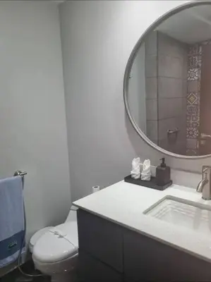 a bathroom with a toilet and a round mirror at Casa Bella in Jacó