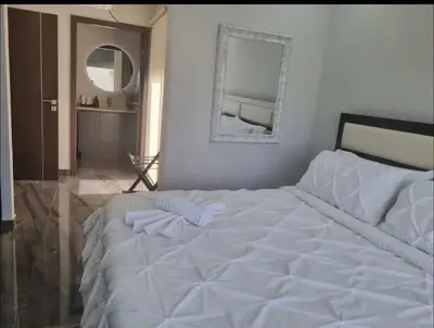 a white bed in a bedroom with a mirror at Casa Bella in Jacó
