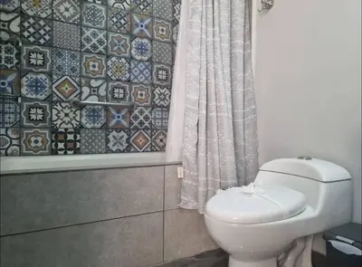 a bathroom with a toilet and a shower and a tile wall at Casa Bella in Jacó
