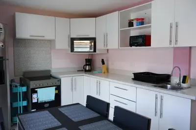 a kitchen with white cabinets and a table and a sink at Casa Pandora Hostel Women Only in San José