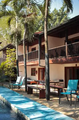 a resort with a pool and chairs and palm trees at Chocolate in Tamarindo