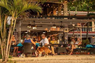 a group of people sitting at a table with a dog at Hotel El Velero in Playa Hermosa