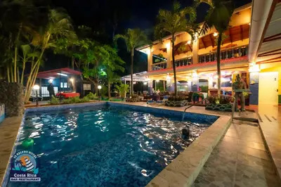 a pool in front of a hotel at night at Hotel El Velero in Playa Hermosa