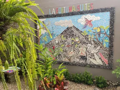 a mosaic on the side of a wall with plants at La Fortuna Lodge by Treebu Hotels in Fortuna
