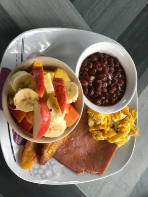 a plate of breakfast food with fruit and a bowl of beans at Apartamentos Equipados DMR #3 in Uvita