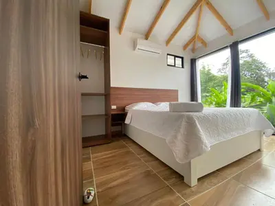 a bedroom with a bed and a large window at Villa Sueños del Arenal in Fortuna