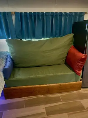 a bed with green and red pillows on it at Ficus Wonders Bus in Monteverde Costa Rica