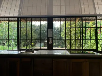 a kitchen with a sink and a large window at Tico casita - Lero Stays in Fortuna