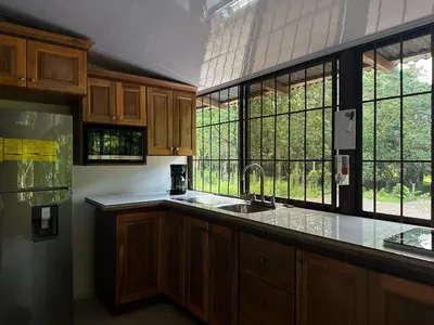 a kitchen with a sink and a large window at Tico casita - Lero Stays in Fortuna