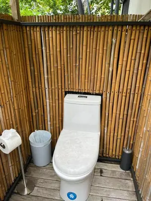 a toilet sitting in front of a wooden fence at Safari tent with private pool close to Manuel Antonio Glamping 1 in Matapalo