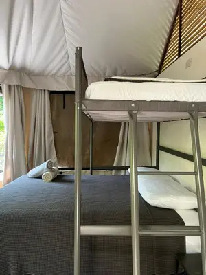 a bedroom with a bunk bed with a ladder and a pillow at Safari tent with private pool close to Manuel Antonio Glamping 1 in Matapalo