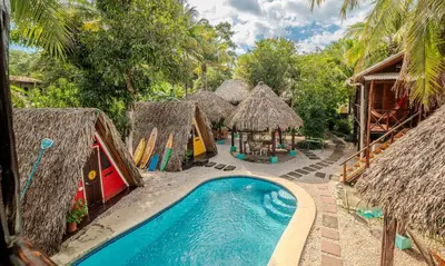 a resort with a swimming pool and some huts at Playa Grande Surf Camp in Playa Grande