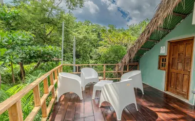 a deck with white chairs and a wooden door at Playa Grande Surf Camp in Playa Grande