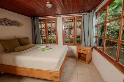 a bedroom with a bed and some windows at Playa Grande Surf Camp in Playa Grande