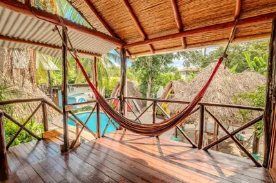 a porch with a hammock and a pool at Playa Grande Surf Camp in Playa Grande