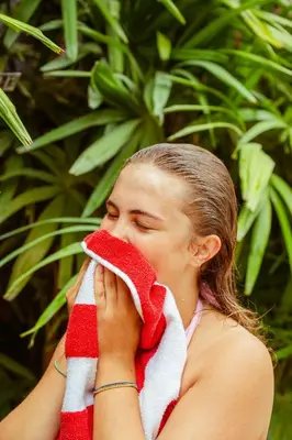 a woman is holding a towel to her face at Playa Grande Surf Camp in Playa Grande