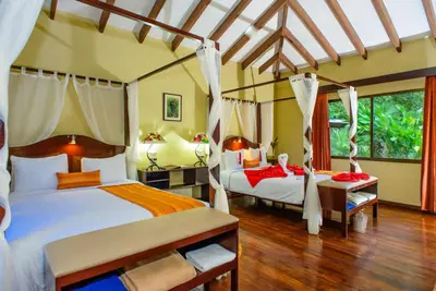 a bedroom with two beds and two chairs at Manatus Hotel in Tortuguero