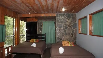 two beds sitting in a room with a window at Manakin Lodge, Monteverde in Monteverde Costa Rica