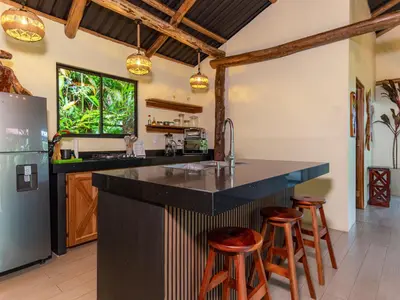 a kitchen with a large black counter and stools at Cabañas Caeli, El Toucan, Peaceful Rainforest Retreat with Stunning Views in Fortuna
