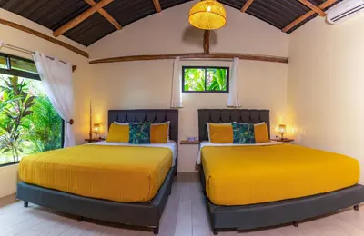 two beds in a room with yellow beds at Cabañas Caeli, El Toucan, Peaceful Rainforest Retreat with Stunning Views in Fortuna