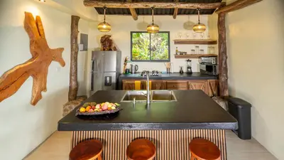 a kitchen with a island with a bowl of fruit on it at Cabañas Caeli, El Toucan, Peaceful Rainforest Retreat with Stunning Views in Fortuna