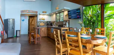 a kitchen with a wooden table and chairs and a counter at Cabañas Caeli, La Perezosa, La Fortuna Rainforest Glass Cabin w Amazing Views in Fortuna
