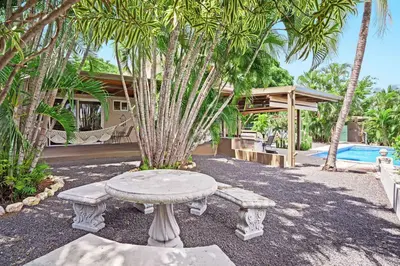 a stone table and benches in front of a house at 8min Walk to Beach, Pool Villa, 24-7 Concierge in Tamarindo