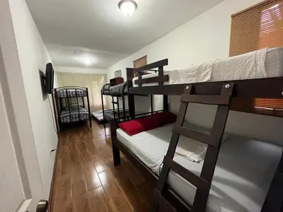 a room with three bunk beds and a couch at La Perla de Cobano in Puntarenas