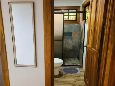 a bathroom with a toilet and a glass shower at Arenal Sweet Cabins in Fortuna