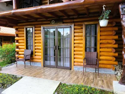 two chairs sitting on a deck in front of a log cabin at Arenal Sweet Cabins in Fortuna