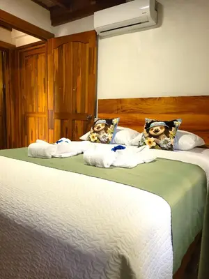 two beds with towels and pillows on them in a bedroom at Arenal Sweet Cabins in Fortuna