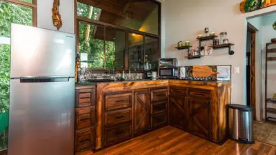 a kitchen with wooden cabinets and a stainless steel refrigerator at Cabañas Caeli, El Congo, La Fortuna Rainforest Glass Cabin w Suite in Fortuna