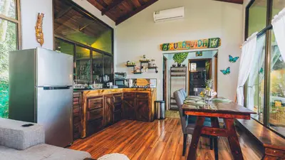 a kitchen with a refrigerator and a wooden table at Cabañas Caeli, El Congo, La Fortuna Rainforest Glass Cabin w Suite in Fortuna